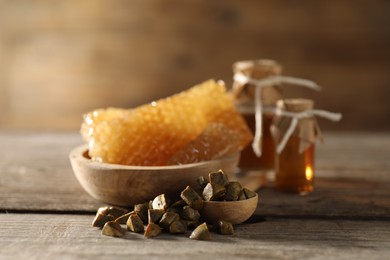 Photo of Natural honey tincture, propolis granules and sweet honeycombs on wooden table, closeup