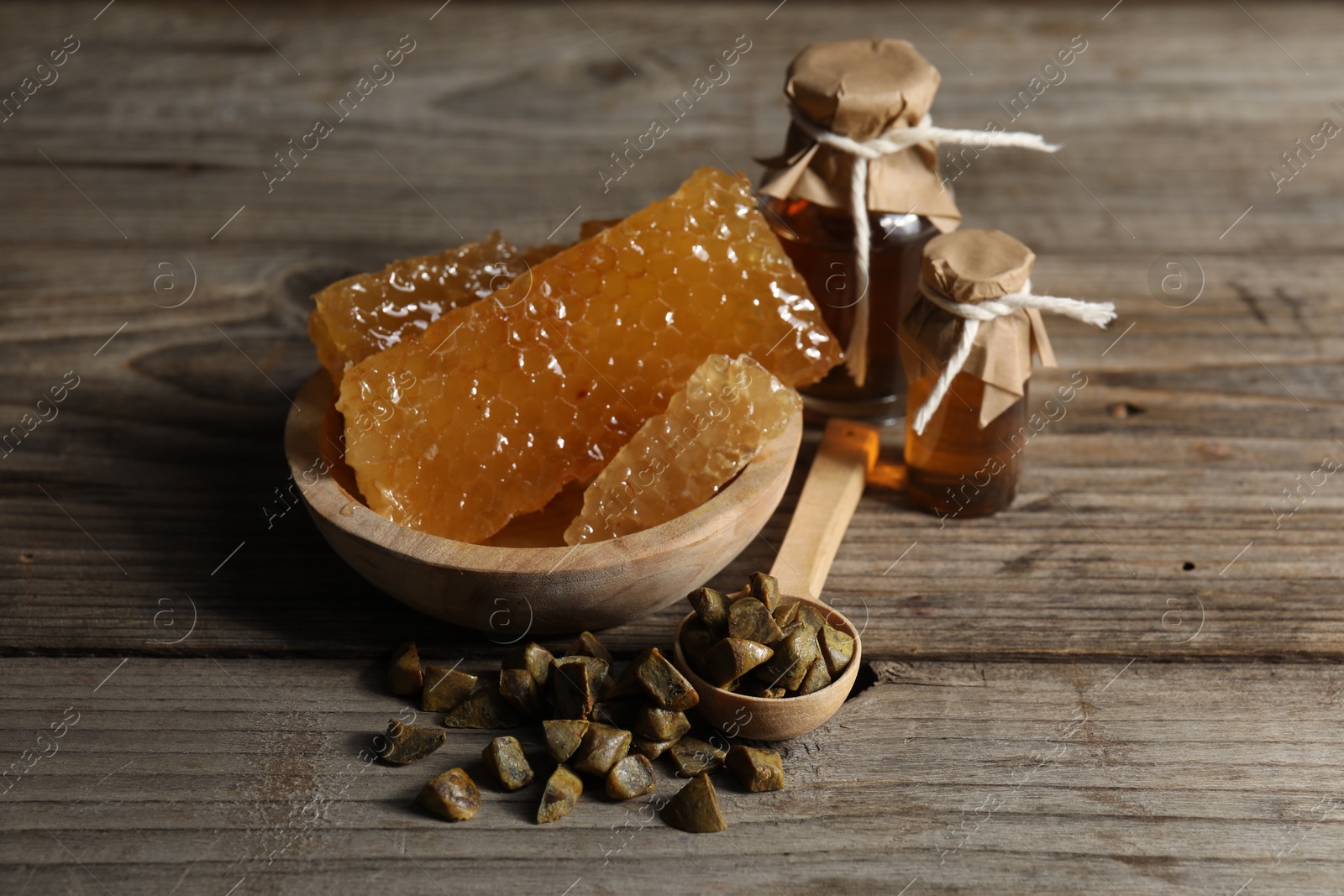 Photo of Natural honey tincture, propolis granules and sweet honeycombs on wooden table