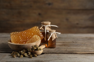 Natural honey tincture, propolis granules and sweet honeycombs on wooden table, space for text