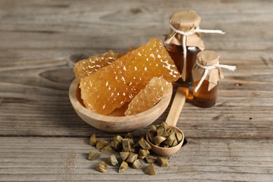 Photo of Natural honey tincture, propolis granules and sweet honeycombs on wooden table