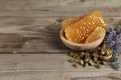 Photo of Natural sweet honeycombs, lavender and propolis granules on wooden table, space for text