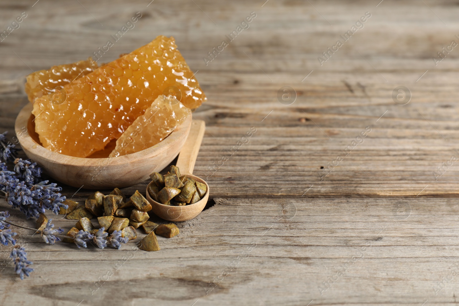 Photo of Natural sweet honeycombs, lavender and propolis granules on wooden table, space for text