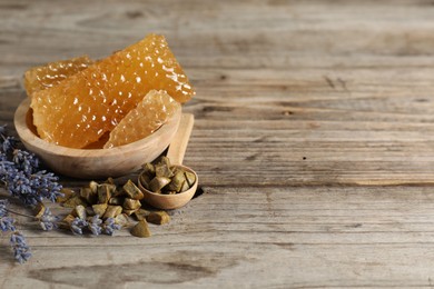 Photo of Natural sweet honeycombs, lavender and propolis granules on wooden table, space for text