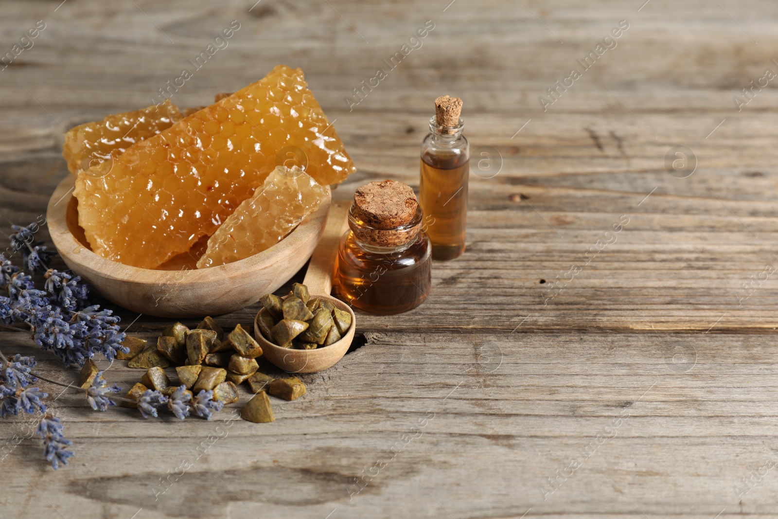 Photo of Natural honey tincture, lavender, propolis granules and sweet honeycombs on wooden table, space for text