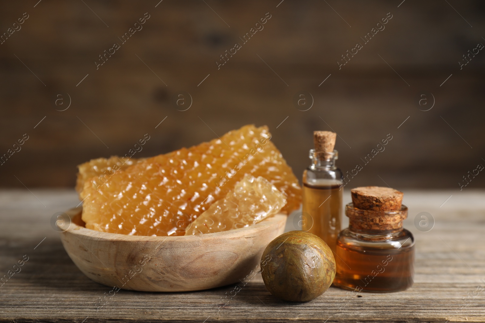 Photo of Natural honey tincture and sweet honeycombs on wooden table, closeup