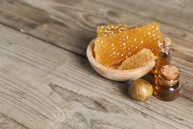 Photo of Natural honey tincture and sweet honeycombs on wooden table, space for text