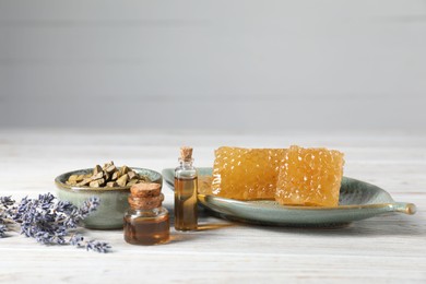 Photo of Natural honey tincture, lavender, propolis granules and sweet honeycombs on white wooden table