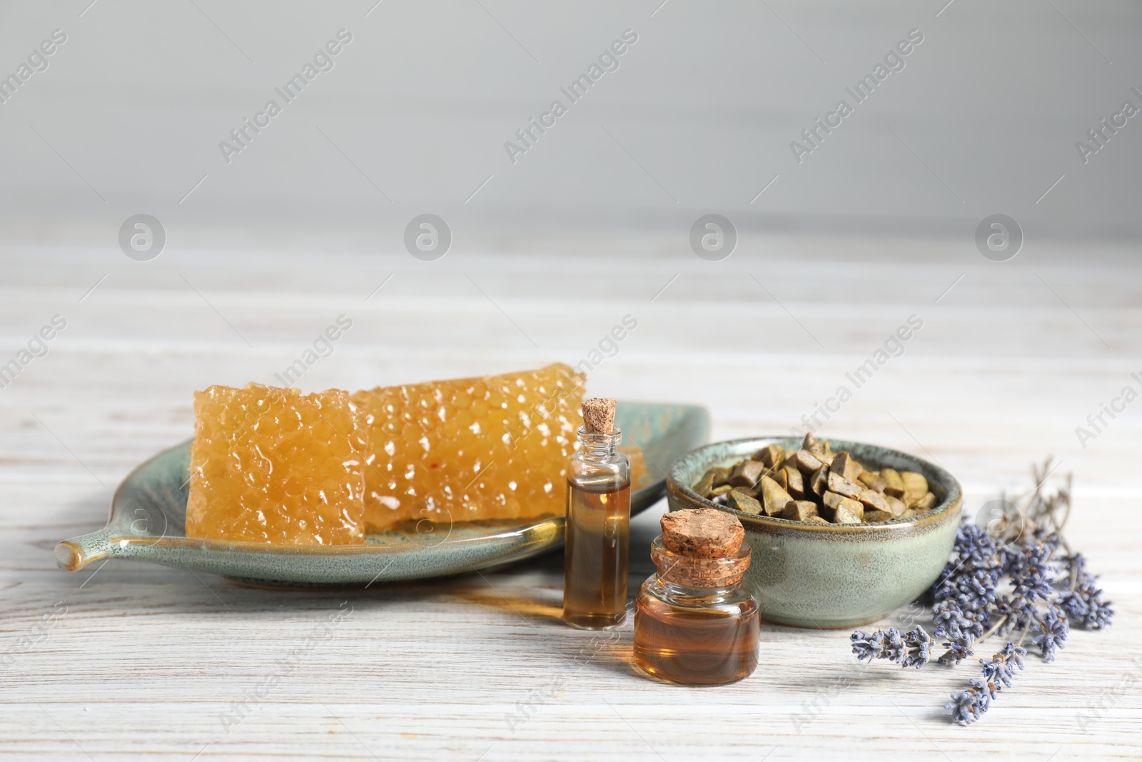 Photo of Natural honey tincture, lavender, propolis granules and sweet honeycombs on white wooden table