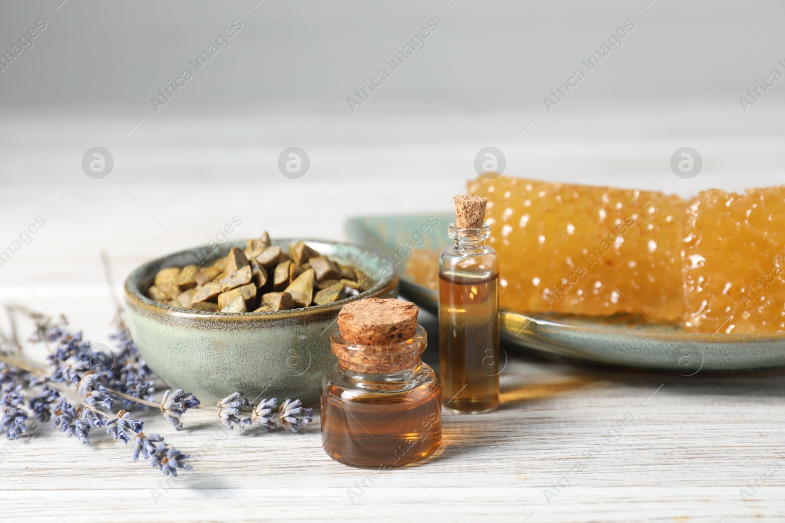 Photo of Natural honey tincture, lavender, propolis granules and sweet honeycombs on white wooden table, closeup