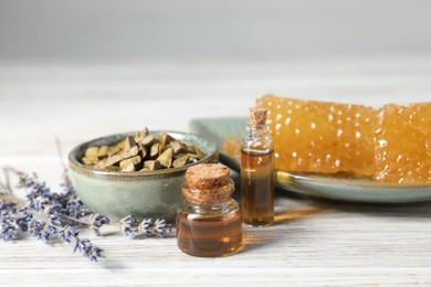 Natural honey tincture, lavender, propolis granules and sweet honeycombs on white wooden table, closeup