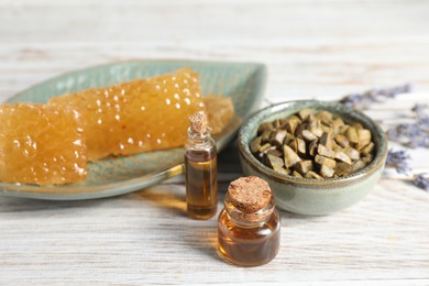 Photo of Natural honey tincture, propolis granules and sweet honeycombs on white wooden table, closeup