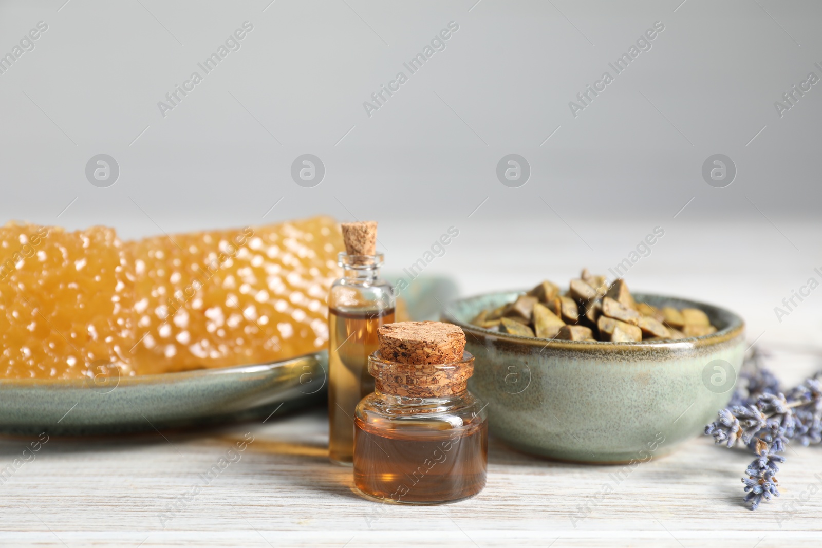 Photo of Natural honey tincture, propolis granules and sweet honeycombs on white wooden table, closeup