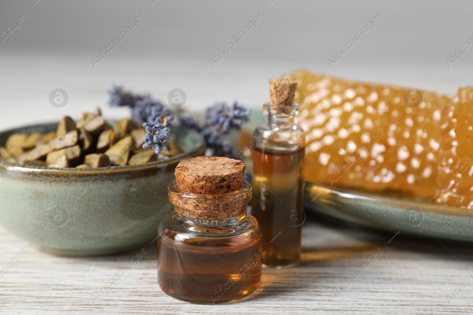 Photo of Natural honey tincture, lavender, propolis granules and sweet honeycombs on white wooden table, closeup