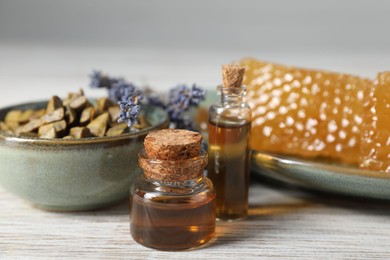 Photo of Natural honey tincture, lavender, propolis granules and sweet honeycombs on white wooden table, closeup