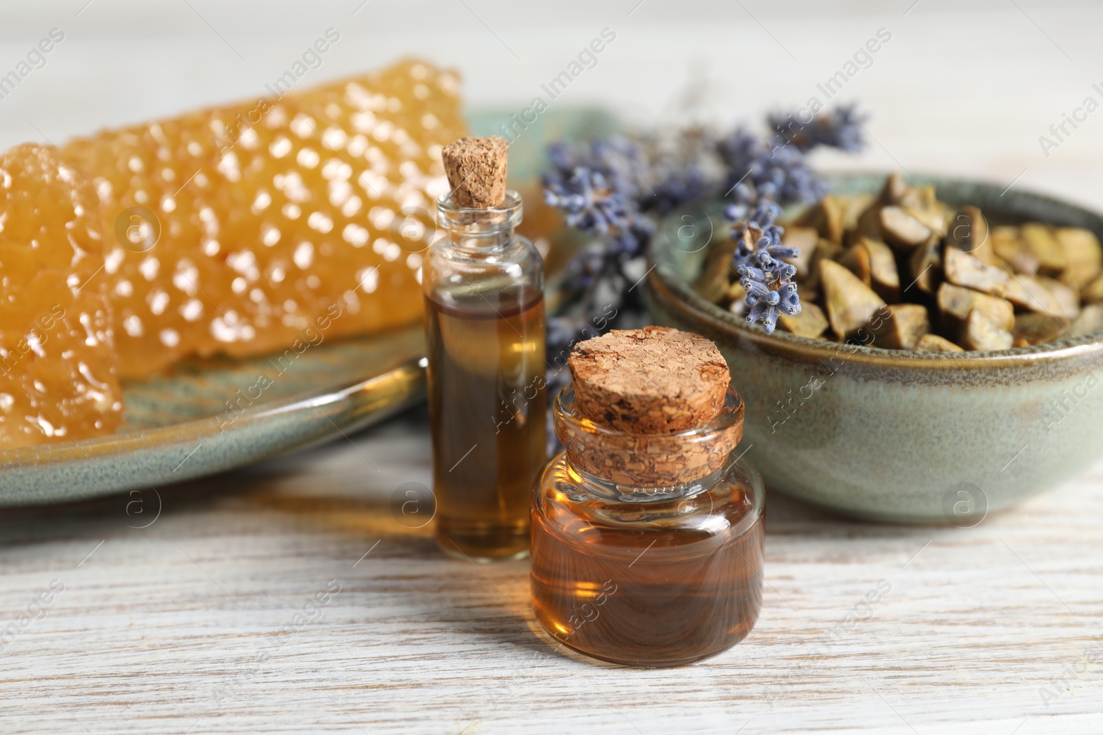 Photo of Natural honey tincture, lavender, propolis granules and sweet honeycombs on white wooden table, closeup