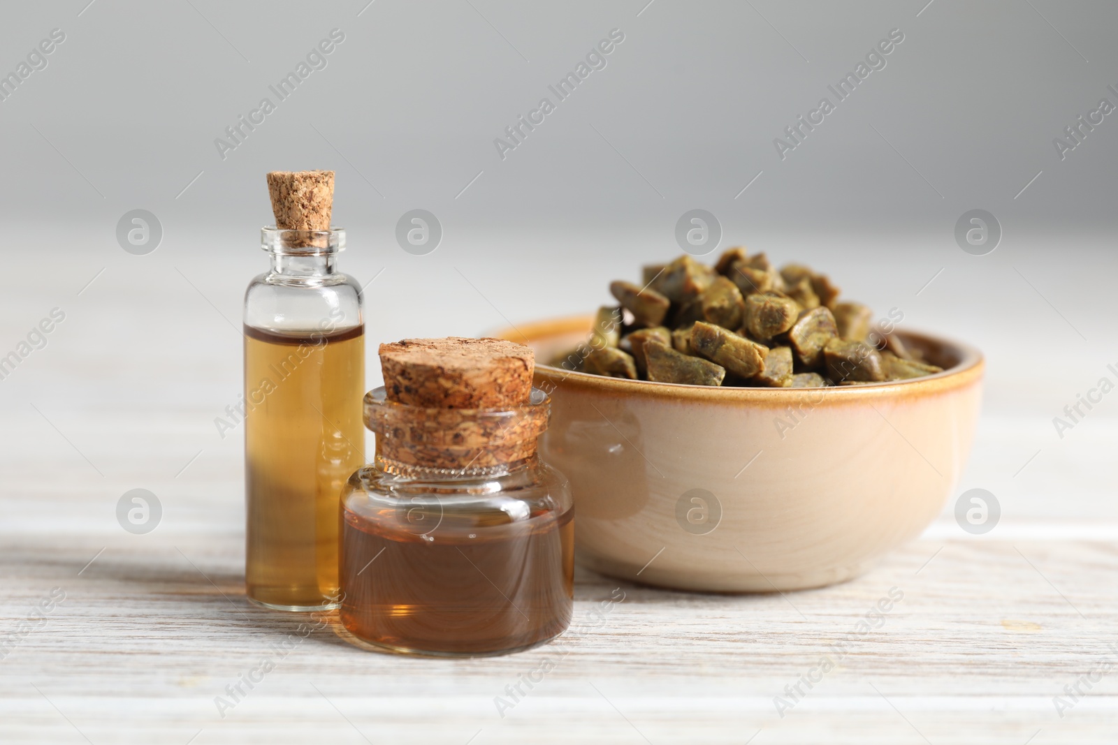 Photo of Natural honey tincture and propolis granules on white wooden table