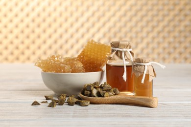 Photo of Natural honey tincture, propolis granules and sweet honeycombs on white wooden table