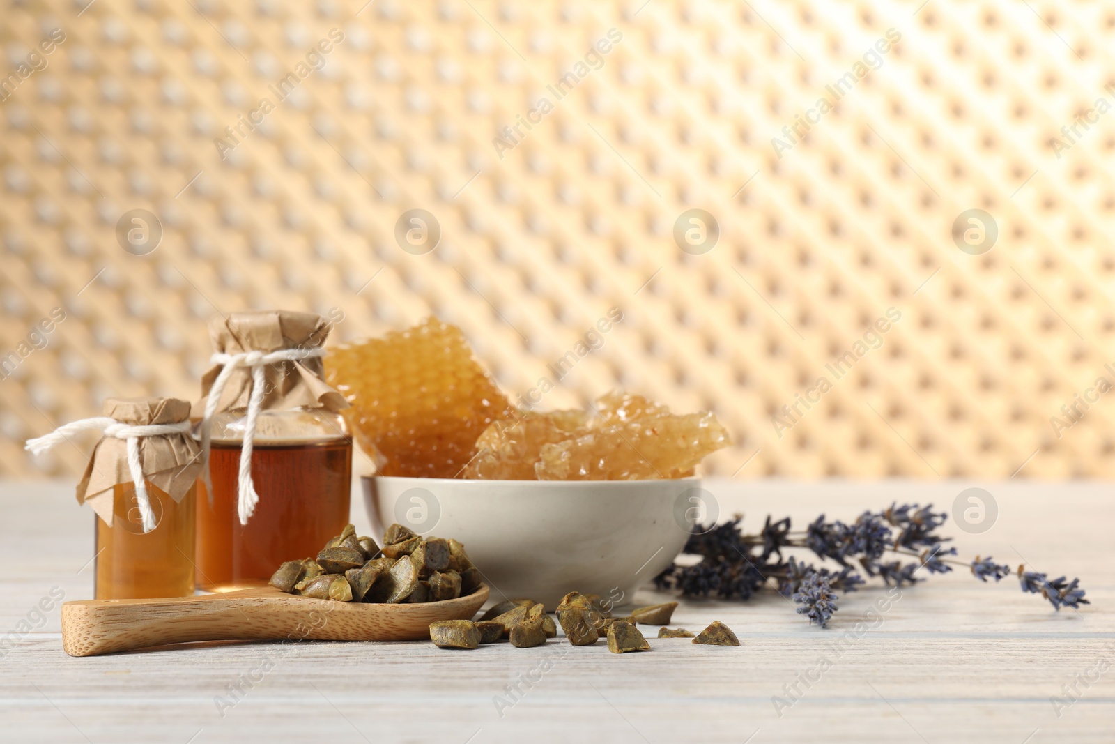 Photo of Natural honey tincture, lavender, propolis granules and sweet honeycombs on white wooden table