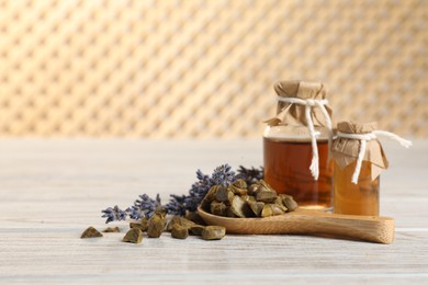 Photo of Natural honey tincture, lavender and propolis granules on white wooden table, space for text