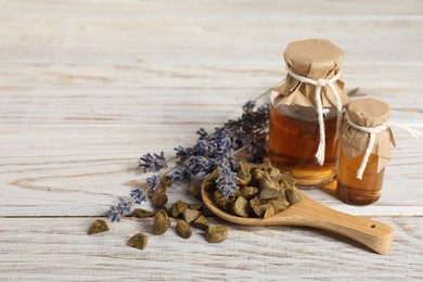 Natural honey tincture, lavender and propolis granules on white wooden table, space for text