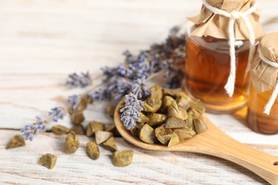 Photo of Natural honey tincture, lavender and propolis granules on white wooden table, closeup