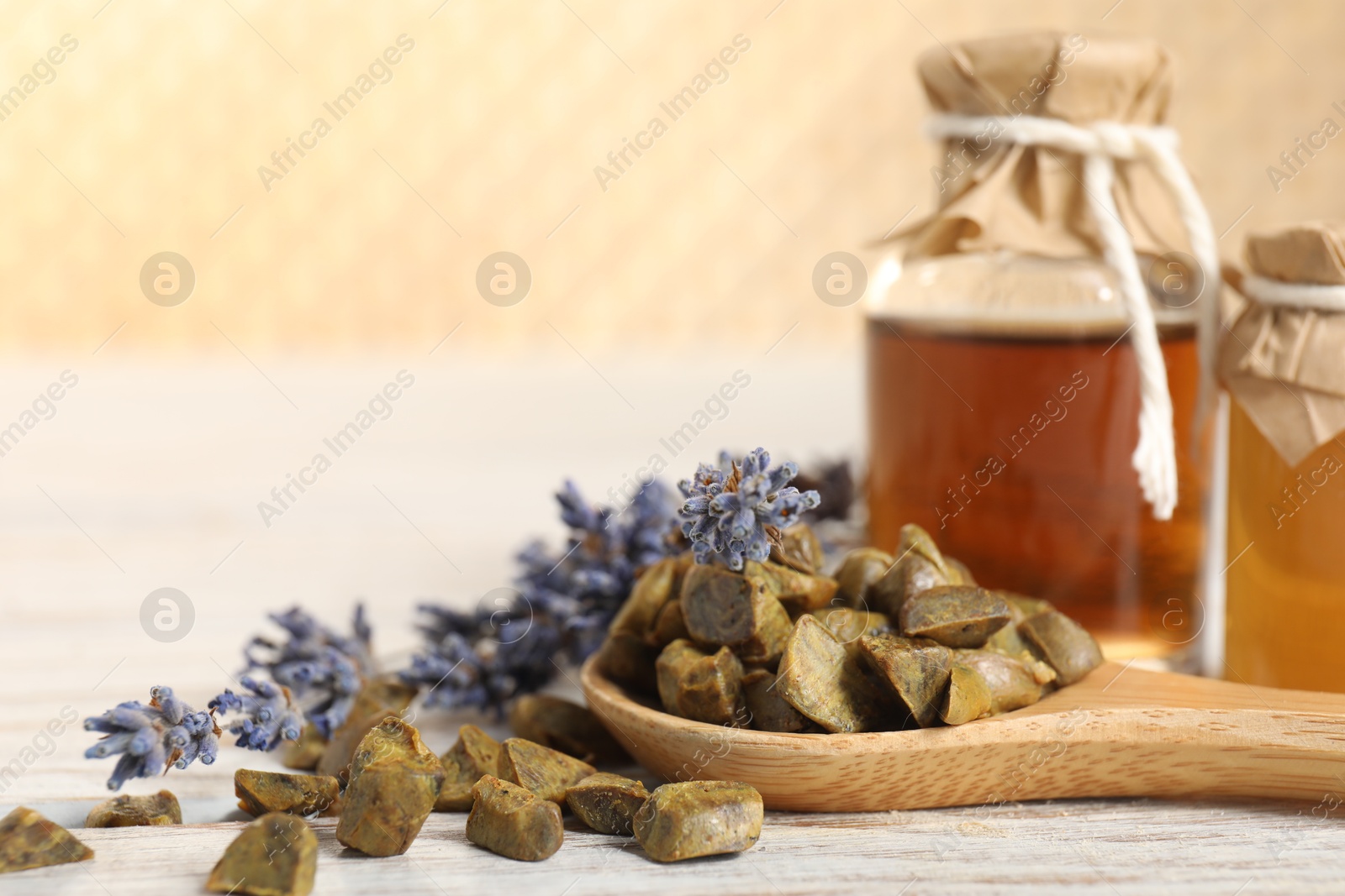 Photo of Natural honey tincture, lavender and propolis granules on white wooden table, closeup. Space for text