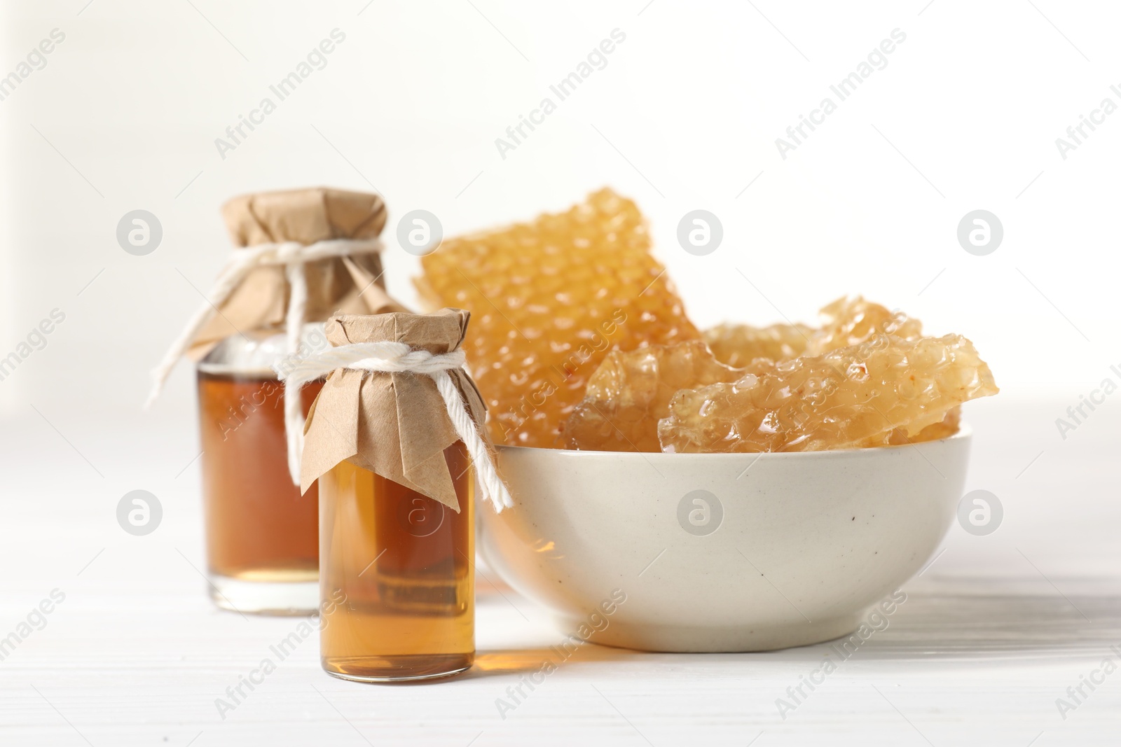 Photo of Natural honey tincture and sweet honeycombs on white wooden table