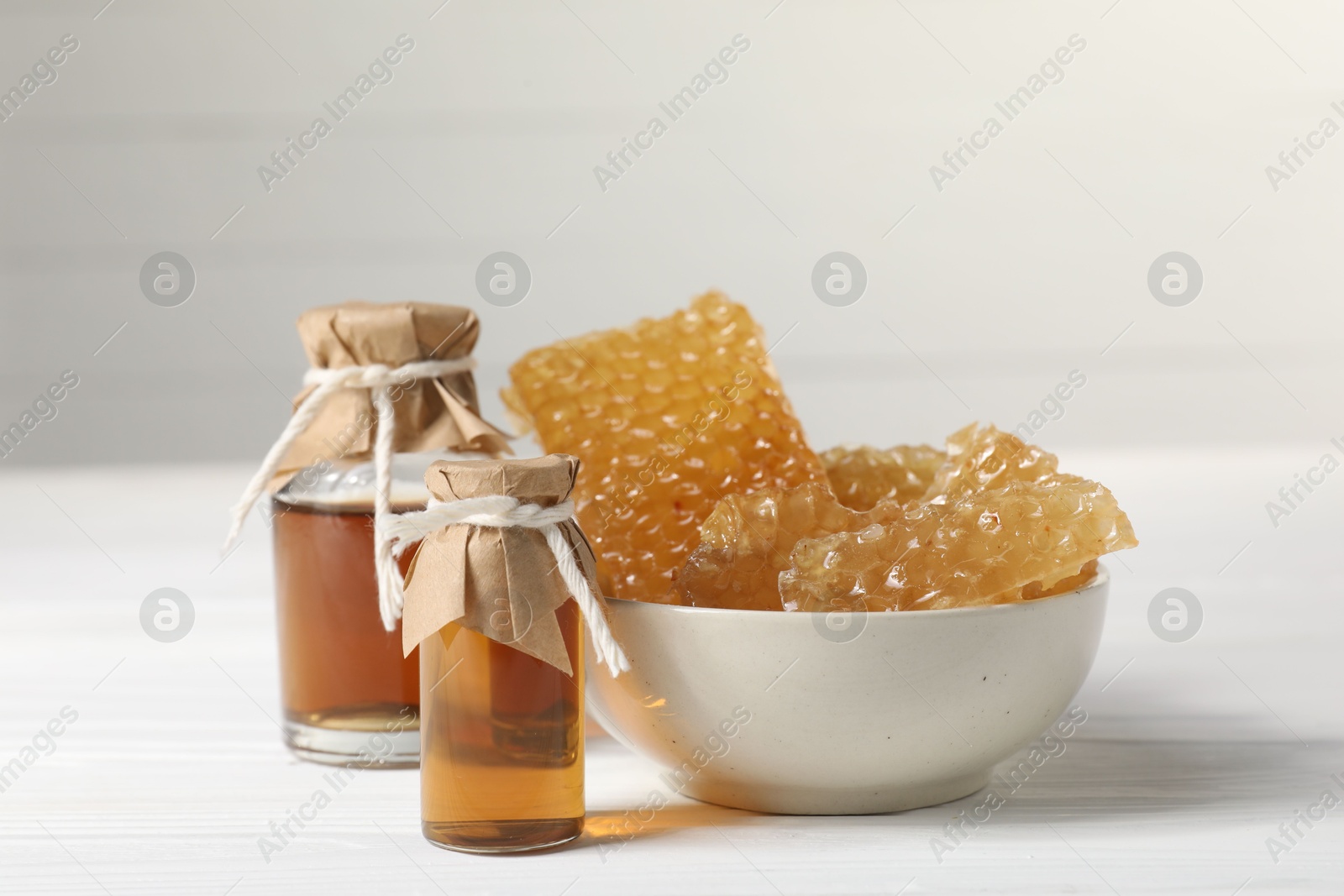 Photo of Natural honey tincture and sweet honeycombs on white wooden table