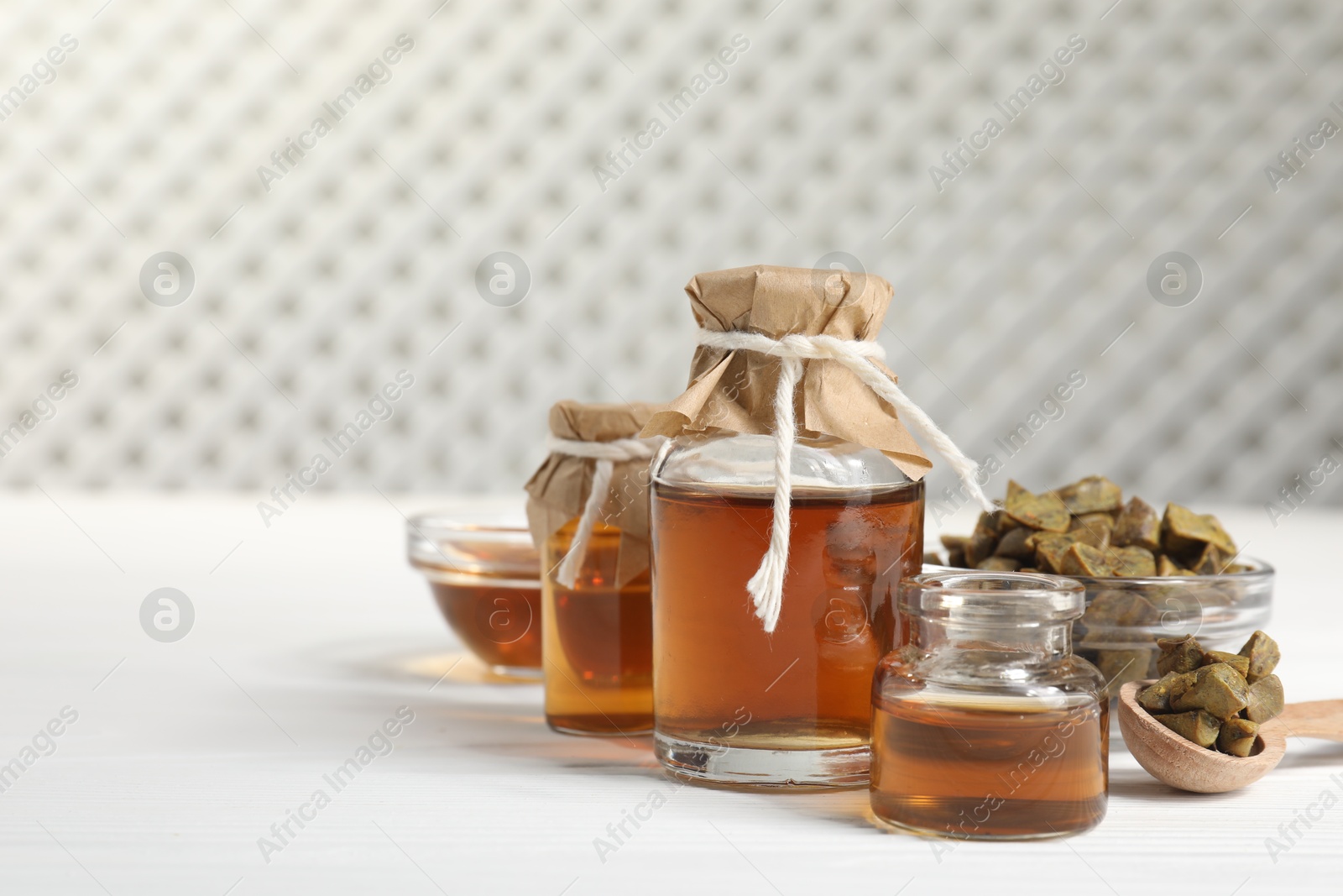 Photo of Natural honey tincture and propolis granules on white wooden table, space for text