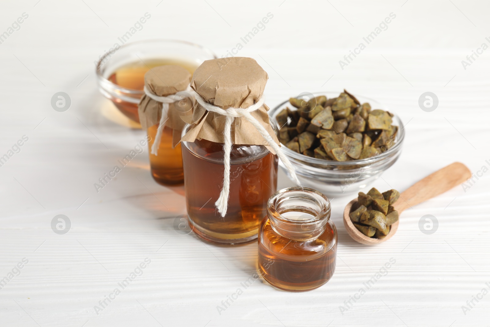 Photo of Natural honey tincture and propolis granules on white wooden table