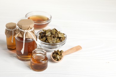 Photo of Natural honey tincture and propolis granules on white wooden table, space for text