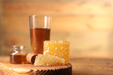 Natural honey tincture and sweet honeycombs on wooden table, closeup. Space for text