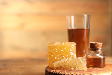 Photo of Natural honey tincture and sweet honeycombs on wooden table, closeup. Space for text