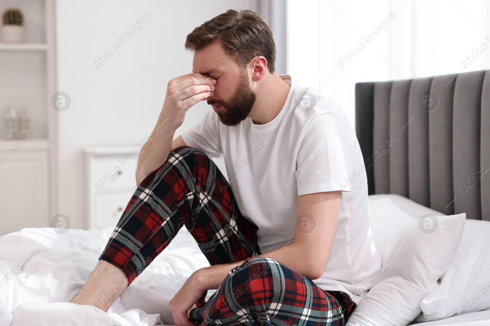 Photo of Young man suffering from headache on bed at morning