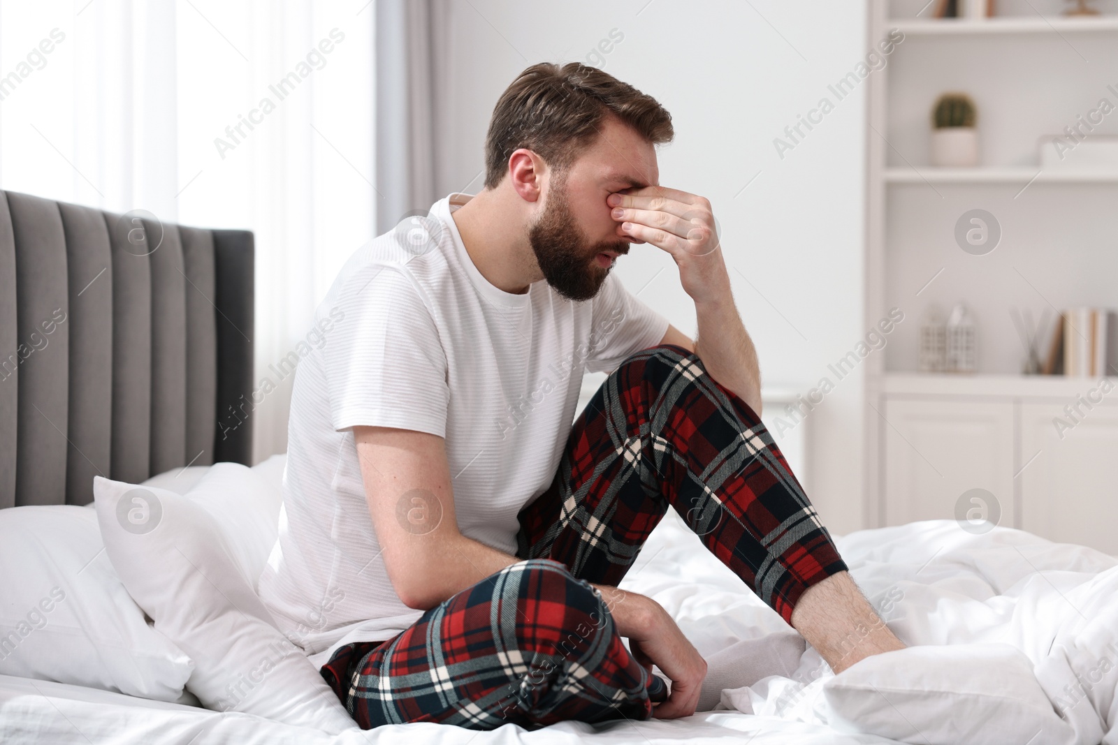 Photo of Young man suffering from headache on bed at morning