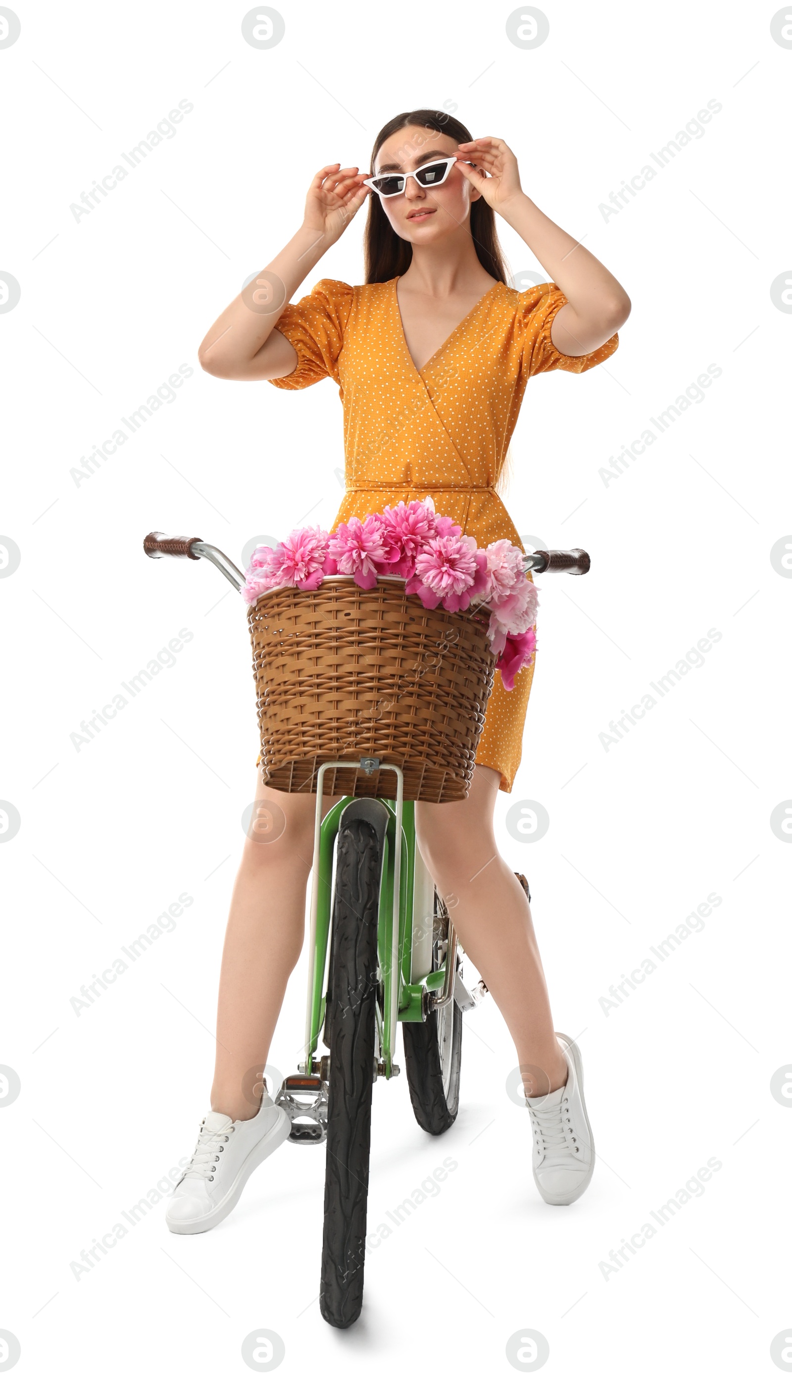 Photo of Woman in sunglasses with bicycle and basket of peony flowers isolated on white