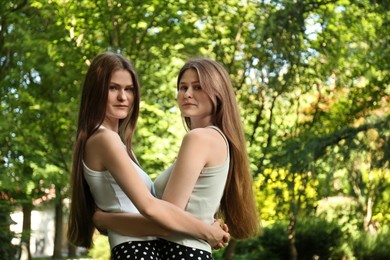 Photo of Portrait of two beautiful twin sisters in park. Space for text