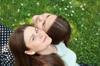Photo of Two beautiful twin sisters spending time together in park, above view