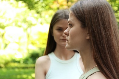 Photo of Two beautiful twin sisters in park, selective focus. Space for text