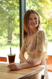 Photo of Beautiful woman with refreshing drink at wooden table in cafe
