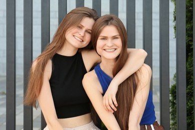 Photo of Two beautiful twin sisters in near metal fence outdoors