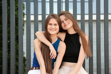 Photo of Two beautiful twin sisters in near metal fence outdoors