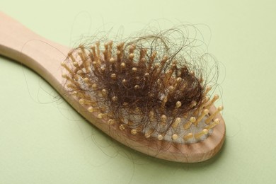 One brush with lost hair on light olive background. Alopecia problem