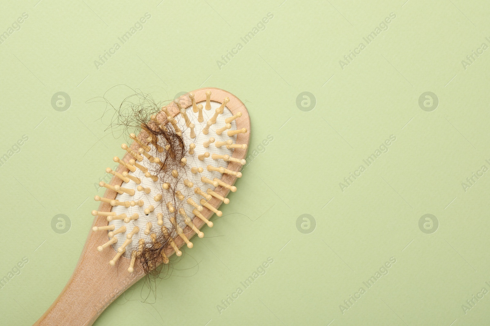 Photo of One brush with lost hair on light olive background, top view. Space for text