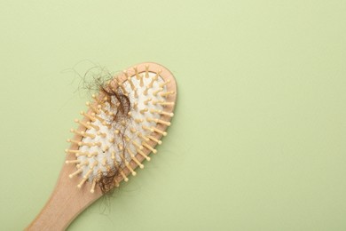 Photo of One brush with lost hair on light olive background, top view. Space for text