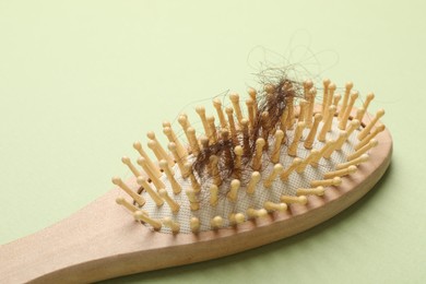 Photo of One brush with lost hair on light olive background, closeup. Alopecia problem