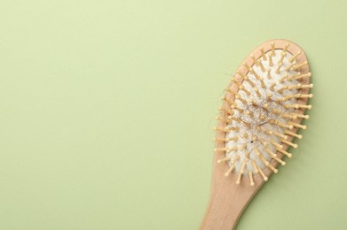 Photo of One brush with lost hair on light olive background, top view. Space for text