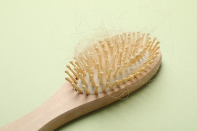 One brush with lost hair on light olive background. Alopecia problem