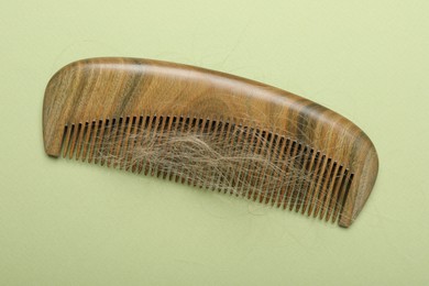 One comb with lost hair on light olive background, top view