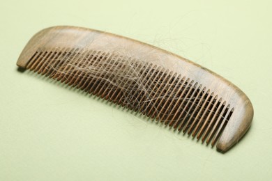 One comb with lost hair on light olive background, closeup